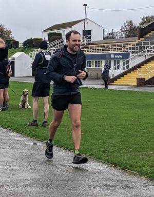 Matt running in shorts and a coat. He is smiling